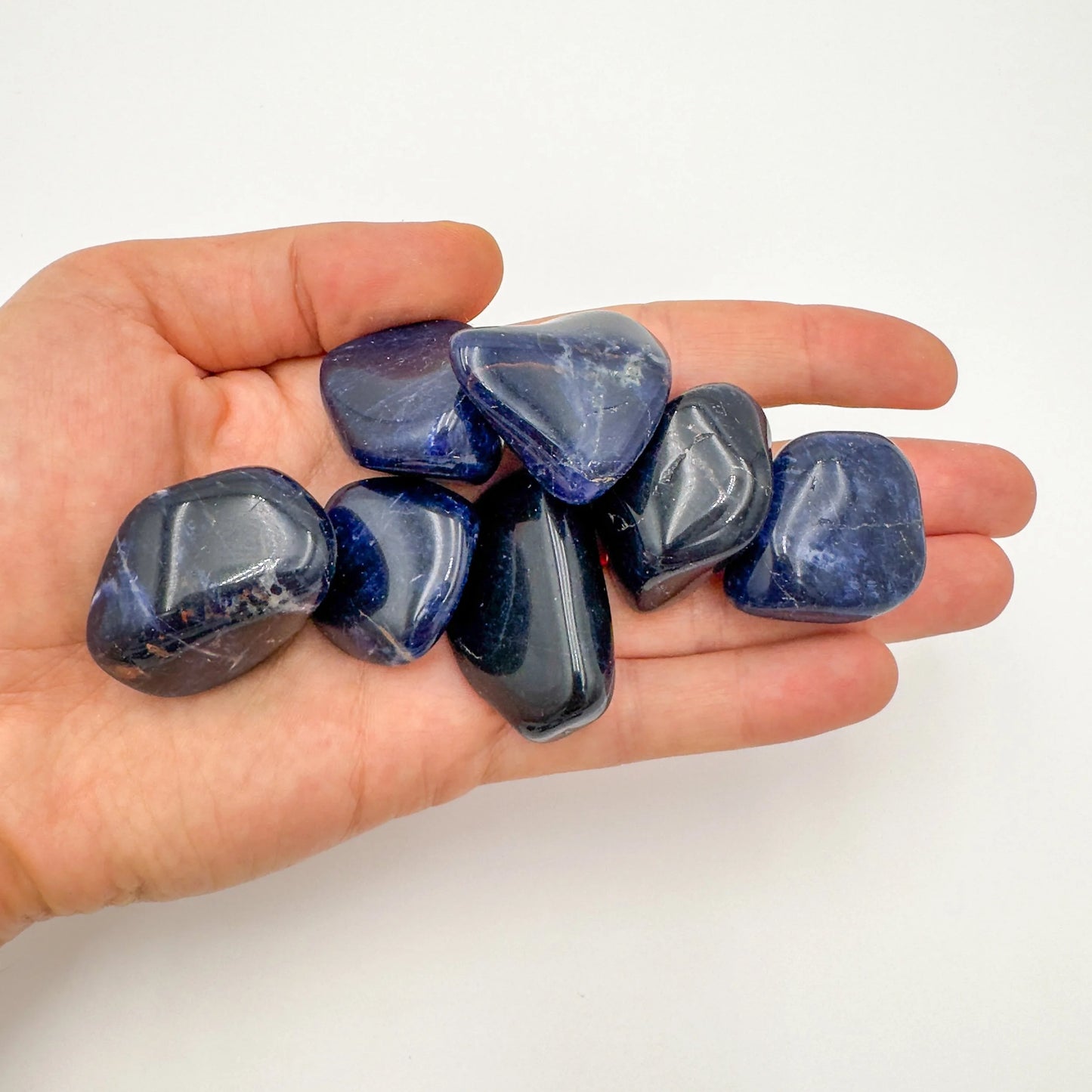 Lifestyle still of Sodalite tumbled stone, from Kunene, Namibia, showing the full body of the piece.
