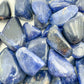 Palm-scale view of a single Sodalite tumbled stone sourced from Kunene, Namibia.