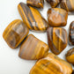 Bird's-eye view of Tiger Eye tumbled stone, from South Africa, showing natural sheen.