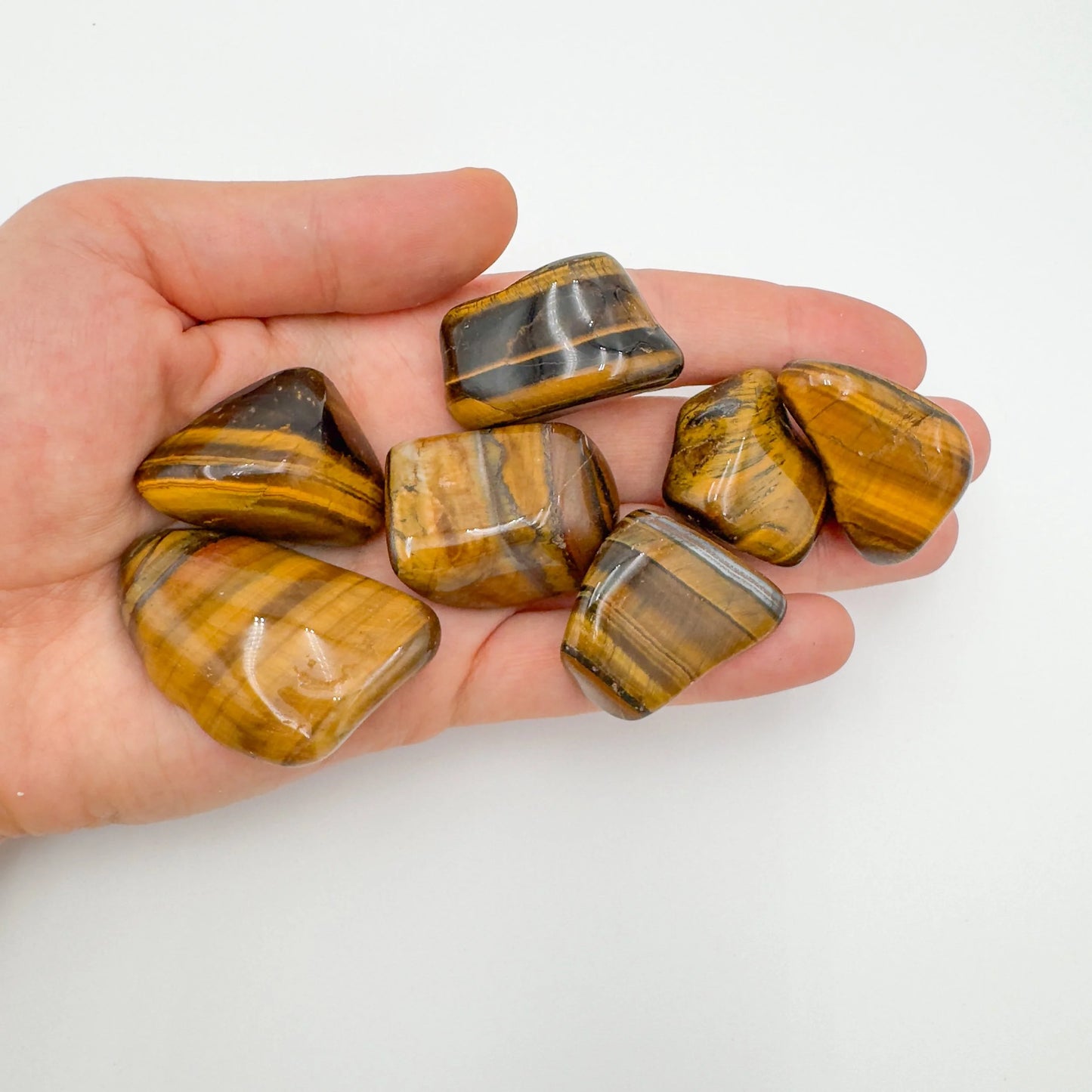 Tabletop view of Tiger Eye tumbled stone, from Northern Cape, South Africa, linked to Confidence, captured in natural daylight.