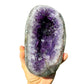 Grade aaa amethyst geode held in hand for size reference