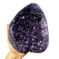 Lifestyle view of a Amethyst raw geode held against natural backdrop.