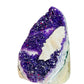 Palm-scale view of a Amethyst raw geode held against natural backdrop.