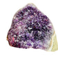 Palm-scale view of a Amethyst raw geode held against natural backdrop.