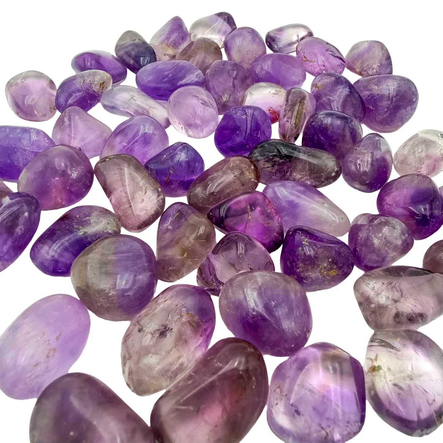 Loose scatter of small Amethyst tumbles showing color variation piece to piece