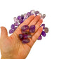 A handful of small Amethyst tumbled stones held in an open palm for scale