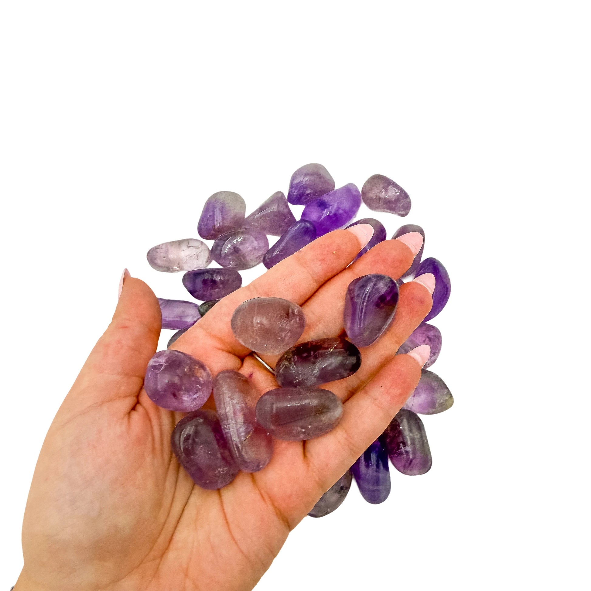 A handful of 1 to 1.5 inch Amethyst tumbled stones held in an open palm for scale