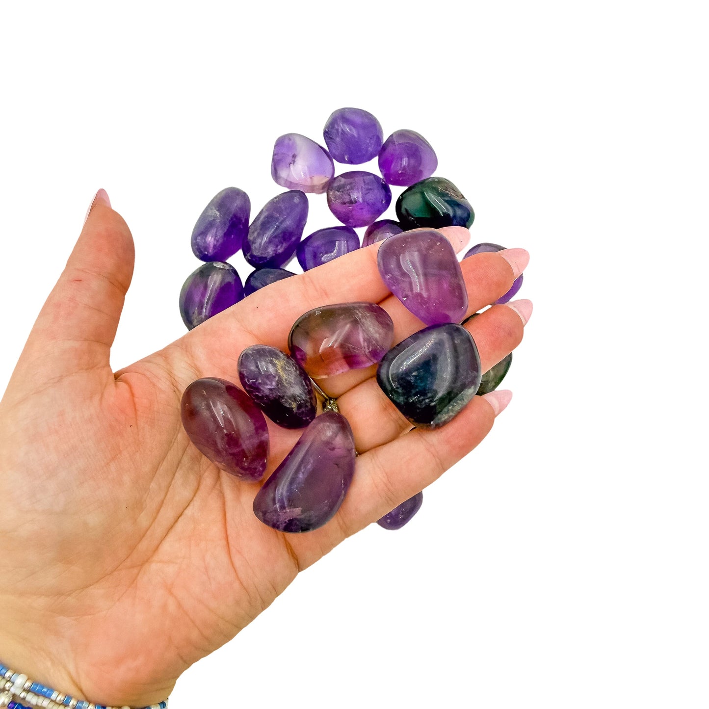 A handful of Ametrine tumbled stones held in an open palm for scale