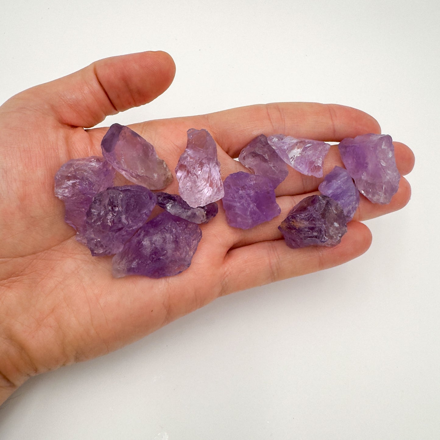 Hand holding small amethyst raw crystals 5-10 grams Brazil scale reference