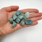 Hand holding small aquamarine raw crystals 5-10 grams Brazil scale reference