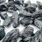 Hand-scale shot of a Black Tourmaline raw stone, sourced from Brazil.