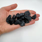 Hand holding small black tourmaline raw crystals 5-10 grams Brazil scale reference
