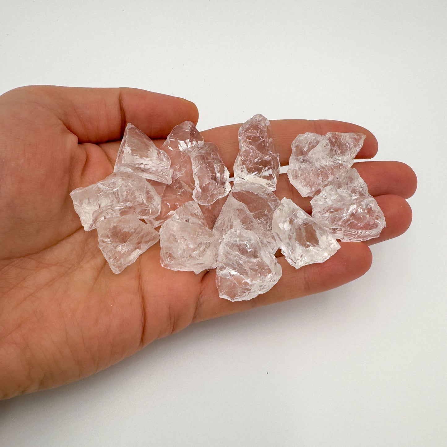 Hand holding small clear quartz raw crystals 5-10 grams Brazil scale reference
