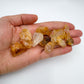 Hand holding small Golden Healer Quartz raw crystals 5-10 grams Brazil scale reference