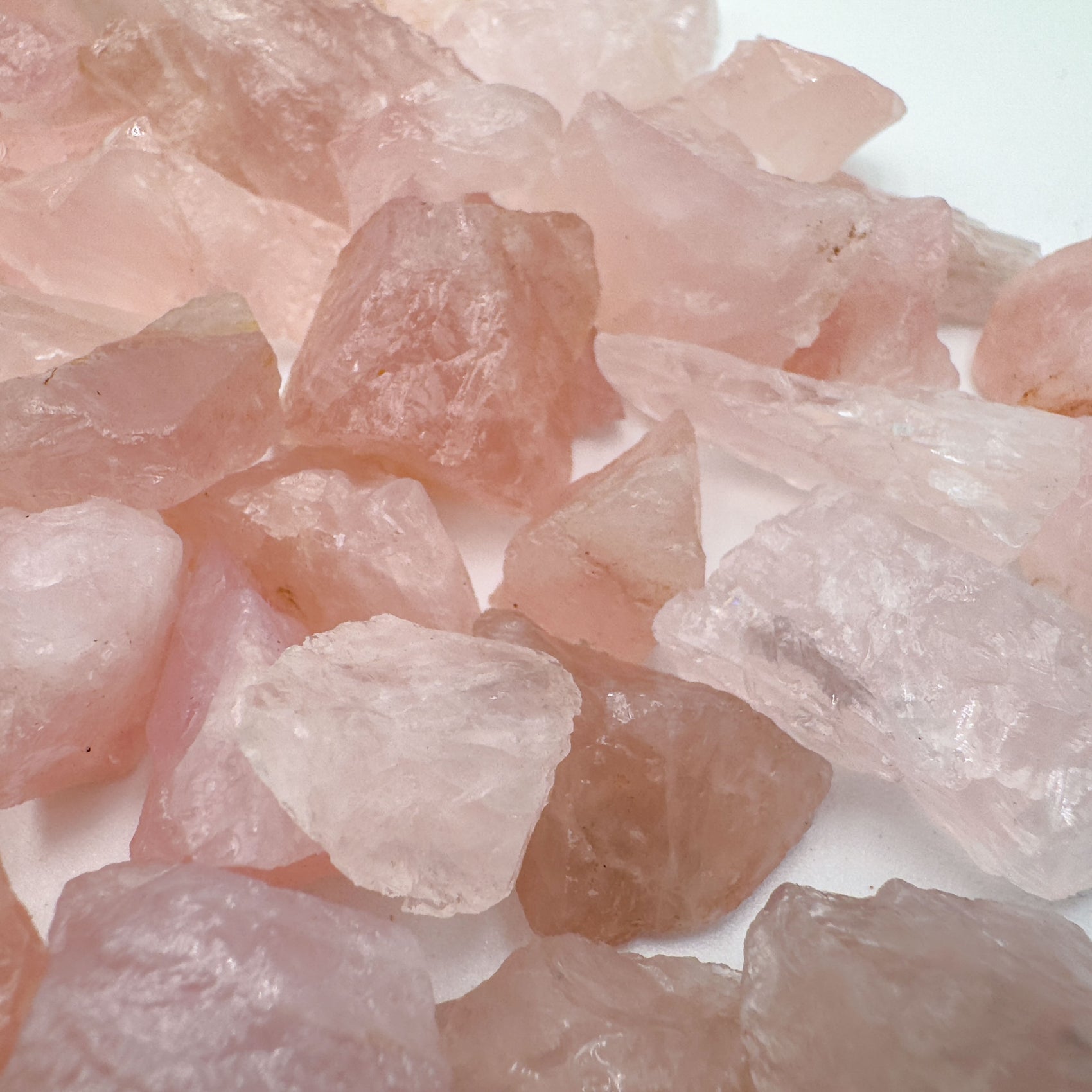 Hand holding small rose quartz raw stones 5-10 grams Brazil scale reference