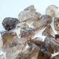 Held against neutral backdrop is a Smoky Quartz raw crystal, from Minas Gerais, Brazil, with subtle natural color showing through.