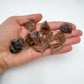 Hand holding small smoky quartz raw crystals 5-10 grams Brazil scale reference