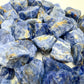 Lifestyle view of a Sodalite raw stone held against natural backdrop.