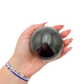 Black Jade sphere no. 1 held in an open hand, showing the true scale of this 2.87 inch, 554 gram orb.