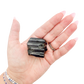 Raw black tourmaline specimen from Madagascar held in hand to show scale