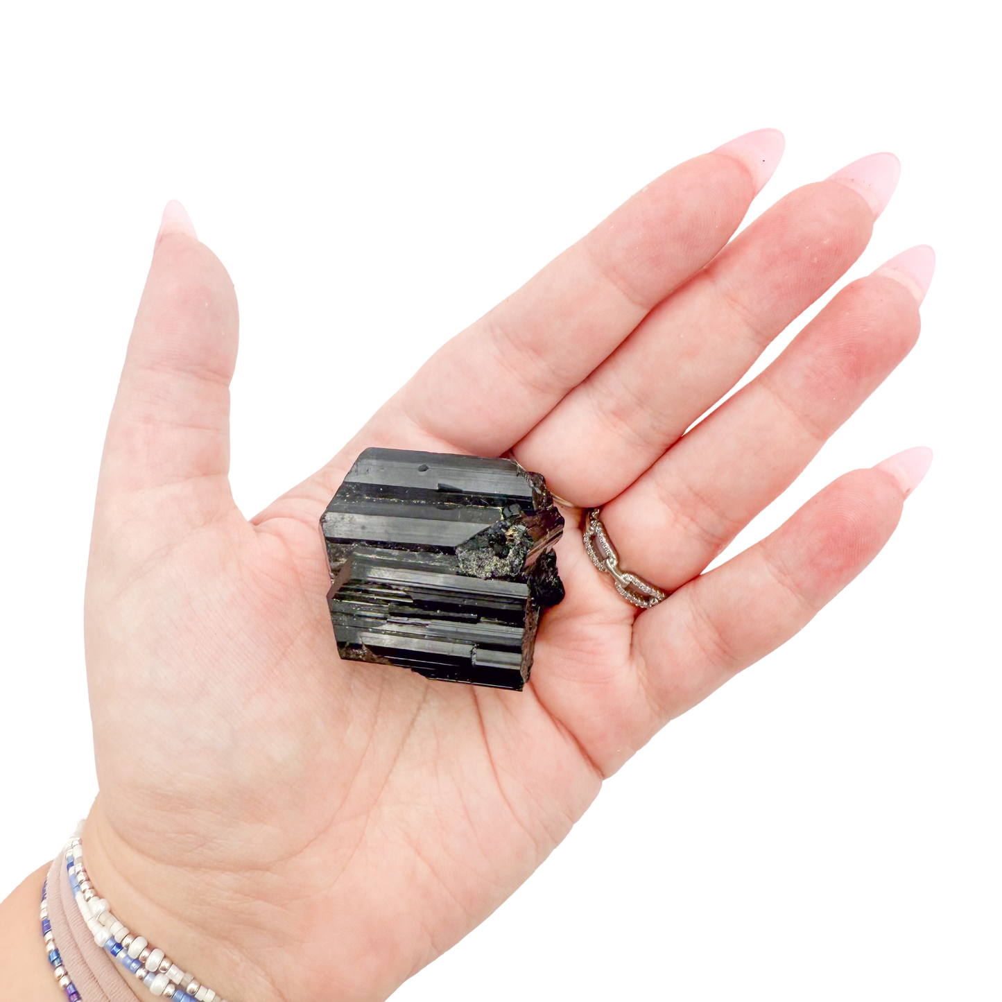 Raw black tourmaline specimen from Madagascar held in hand to show scale