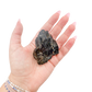 Raw black tourmaline specimen from Madagascar held in hand to show scale
