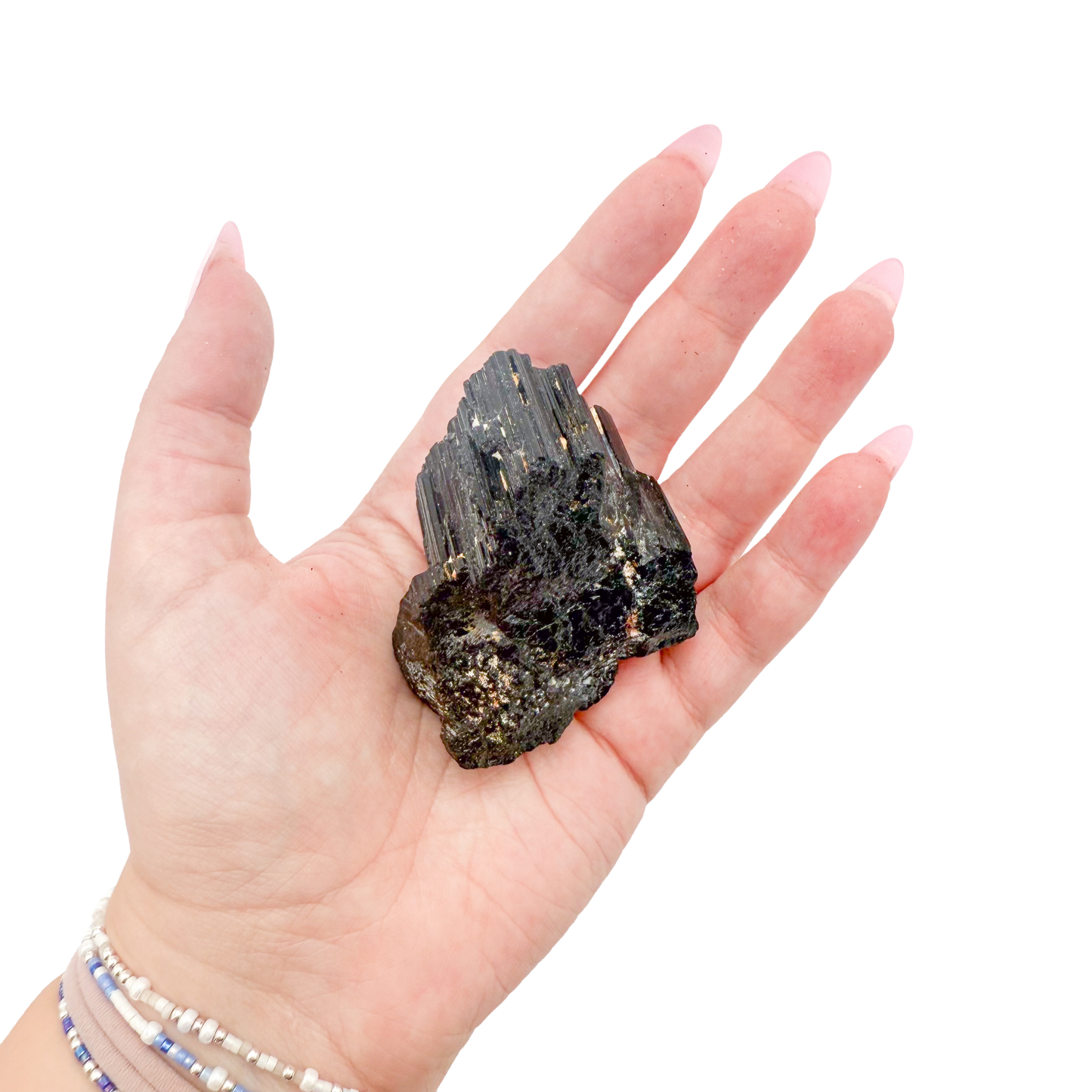 Raw black tourmaline specimen from Madagascar held in hand to show scale