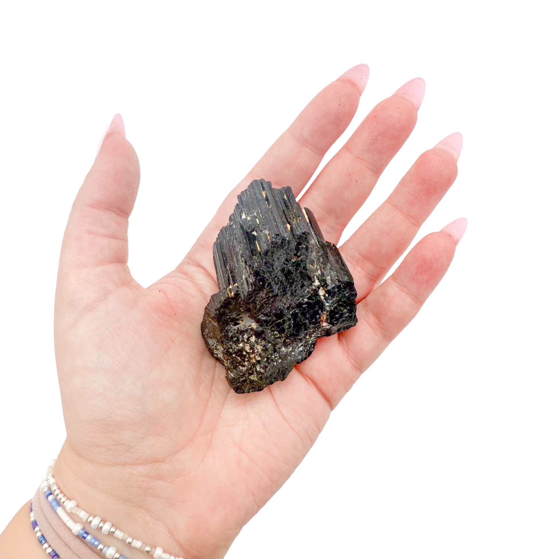 Raw black tourmaline specimen from Madagascar held in hand to show scale