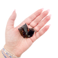 Raw black tourmaline specimen from Madagascar held in hand to show scale