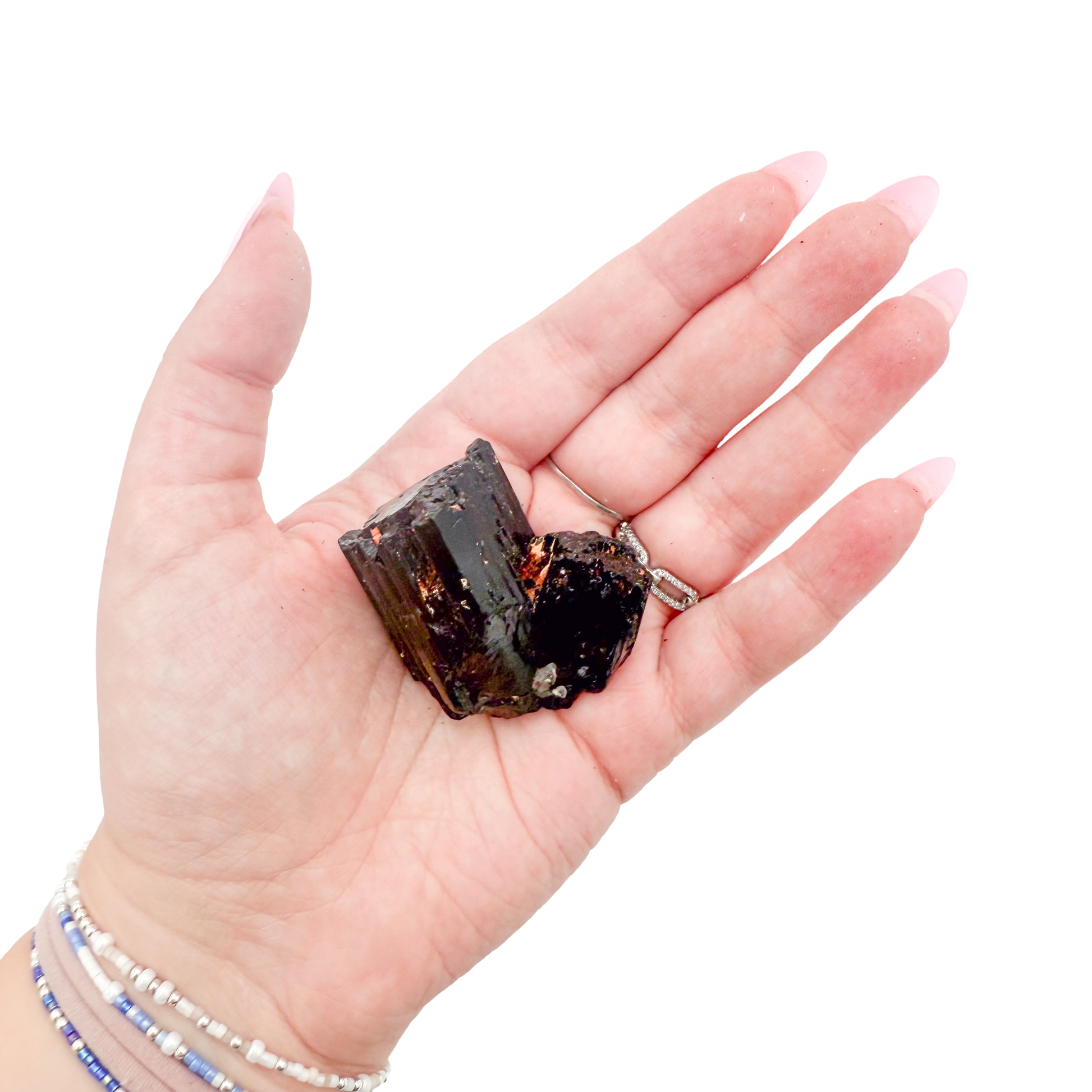 Raw black tourmaline specimen from Madagascar held in hand to show scale