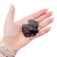 Raw black tourmaline specimen from Madagascar held in hand to show scale
