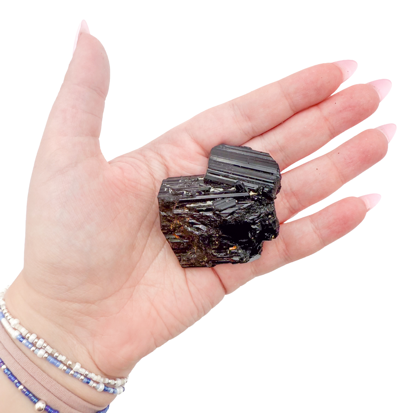 Raw black tourmaline specimen from Madagascar held in hand to show scale