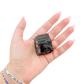 Raw black tourmaline specimen from Madagascar held in hand to show scale