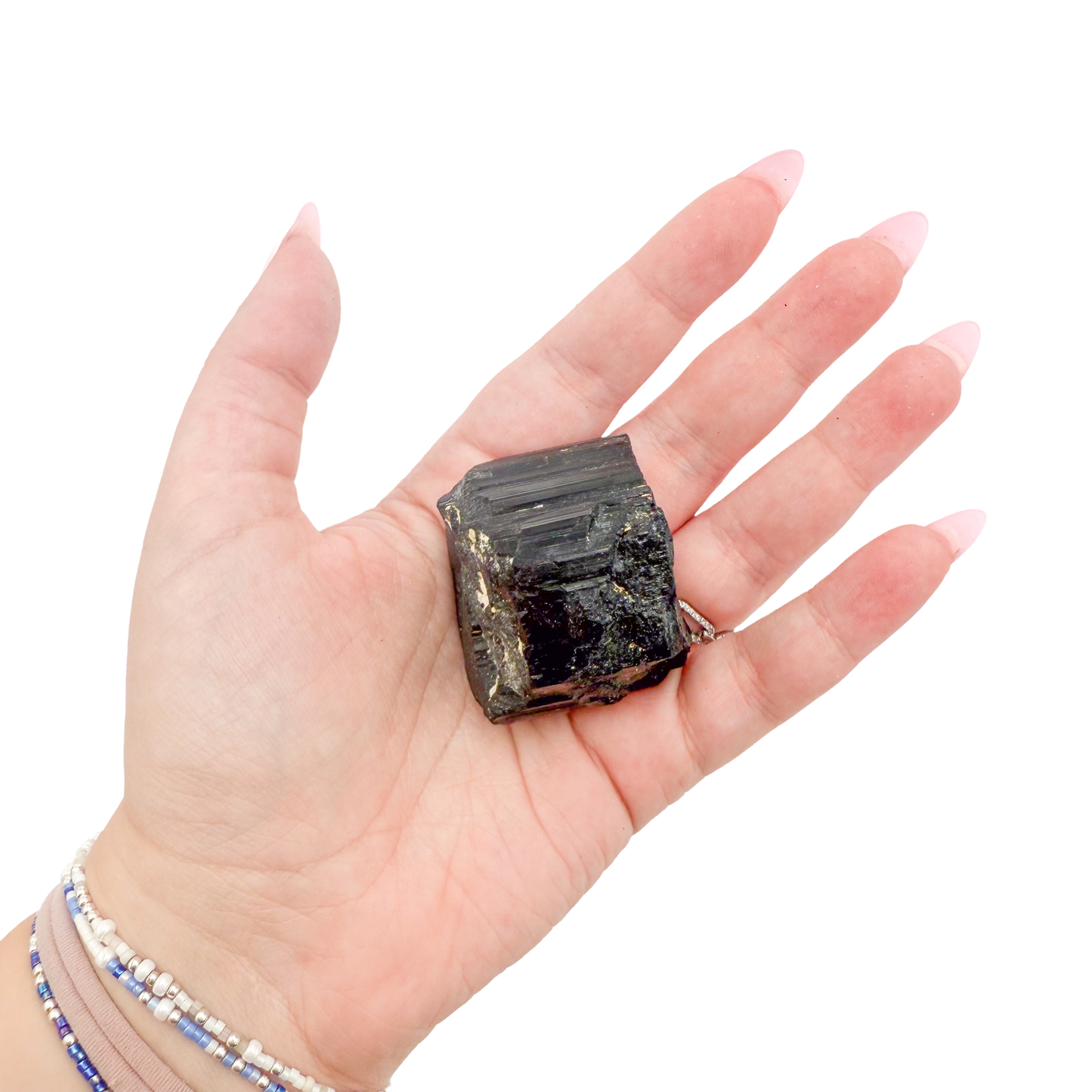 Raw black tourmaline specimen from Madagascar held in hand to show scale