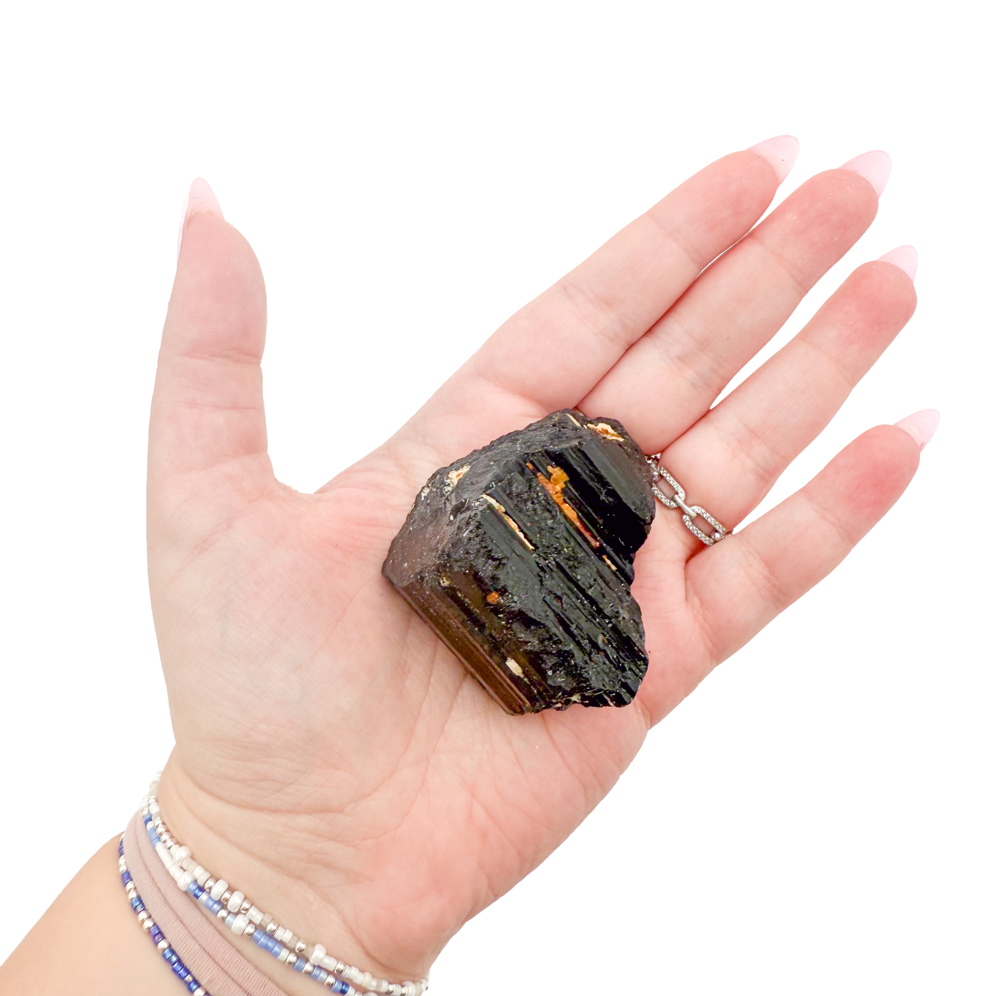 Raw black tourmaline specimen from Madagascar held in hand to show scale