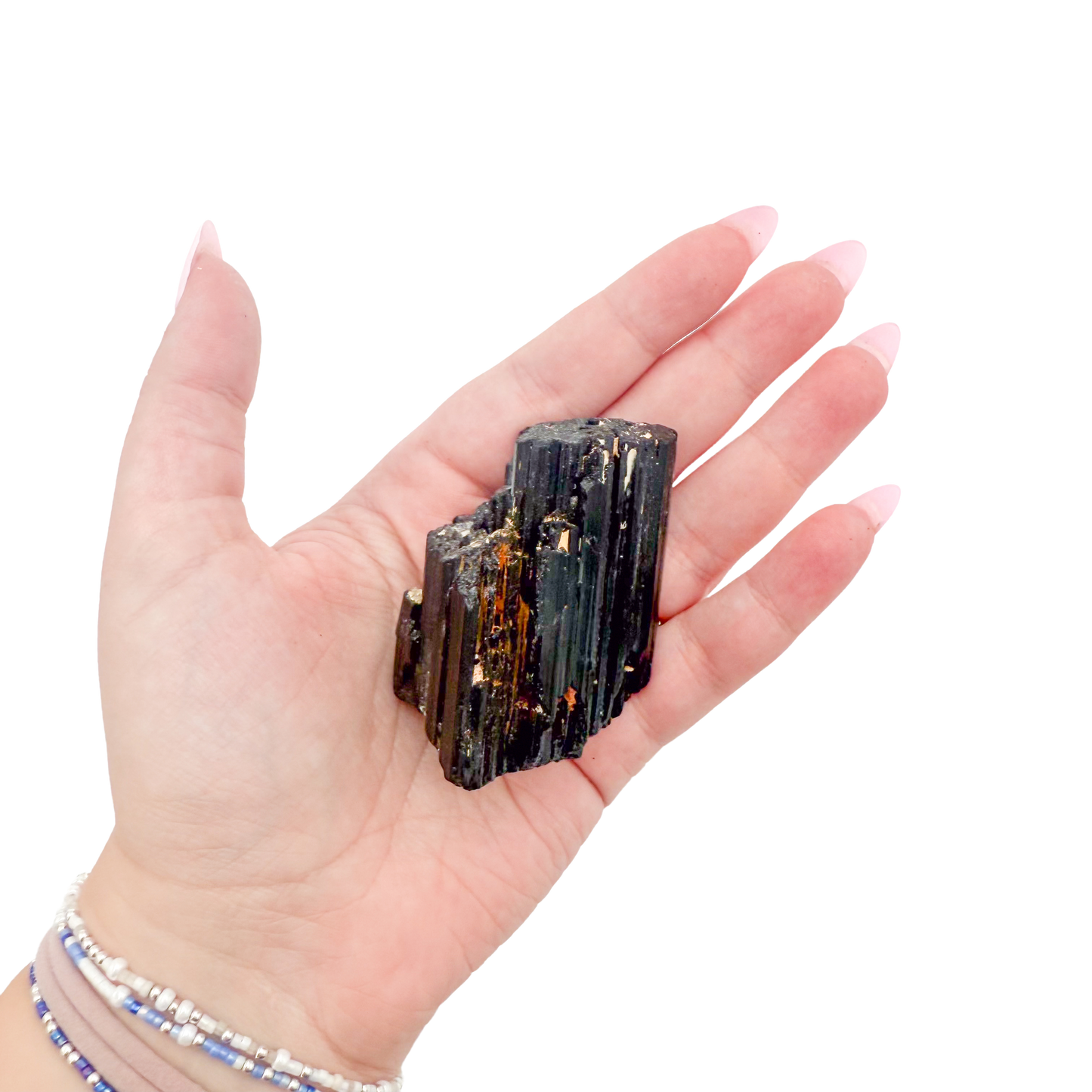 Raw black tourmaline specimen from Madagascar held in hand to show scale