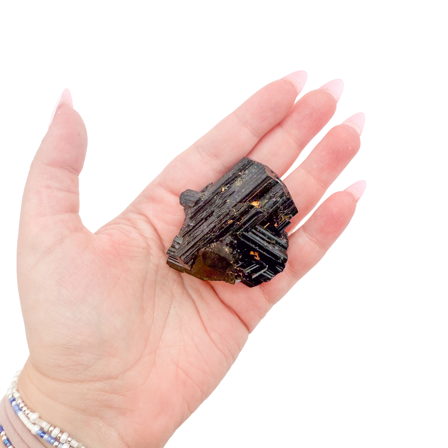 Raw black tourmaline specimen from Madagascar held in hand to show scale