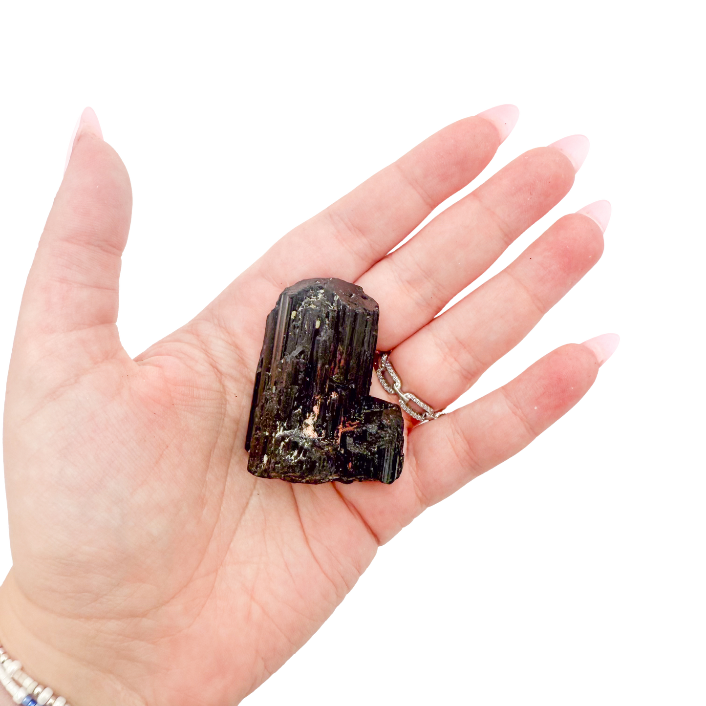 Raw black tourmaline specimen from Madagascar held in hand to show scale