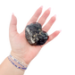 Raw black tourmaline specimen from Madagascar held in hand to show scale