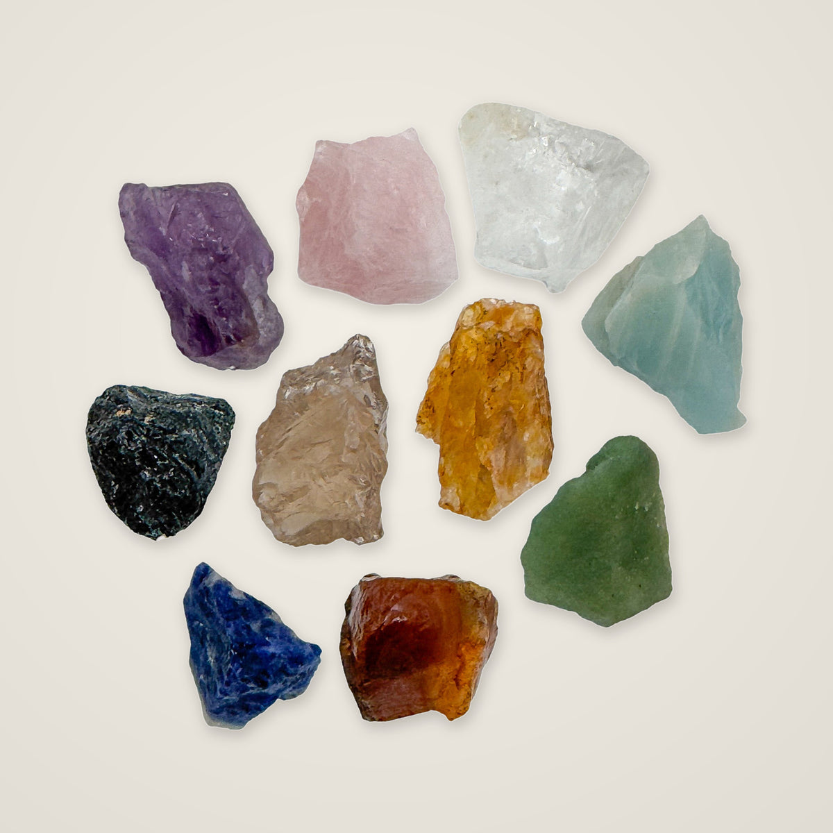 Ten rough stones from the large Brazilian raw crystal set on a warm cream background