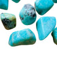Lifestyle view of a Amazonite tumbled stone held against natural backdrop, sourced from Madagascar.