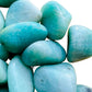 Lifestyle view of a single Amazonite tumbled stone from Brazil.