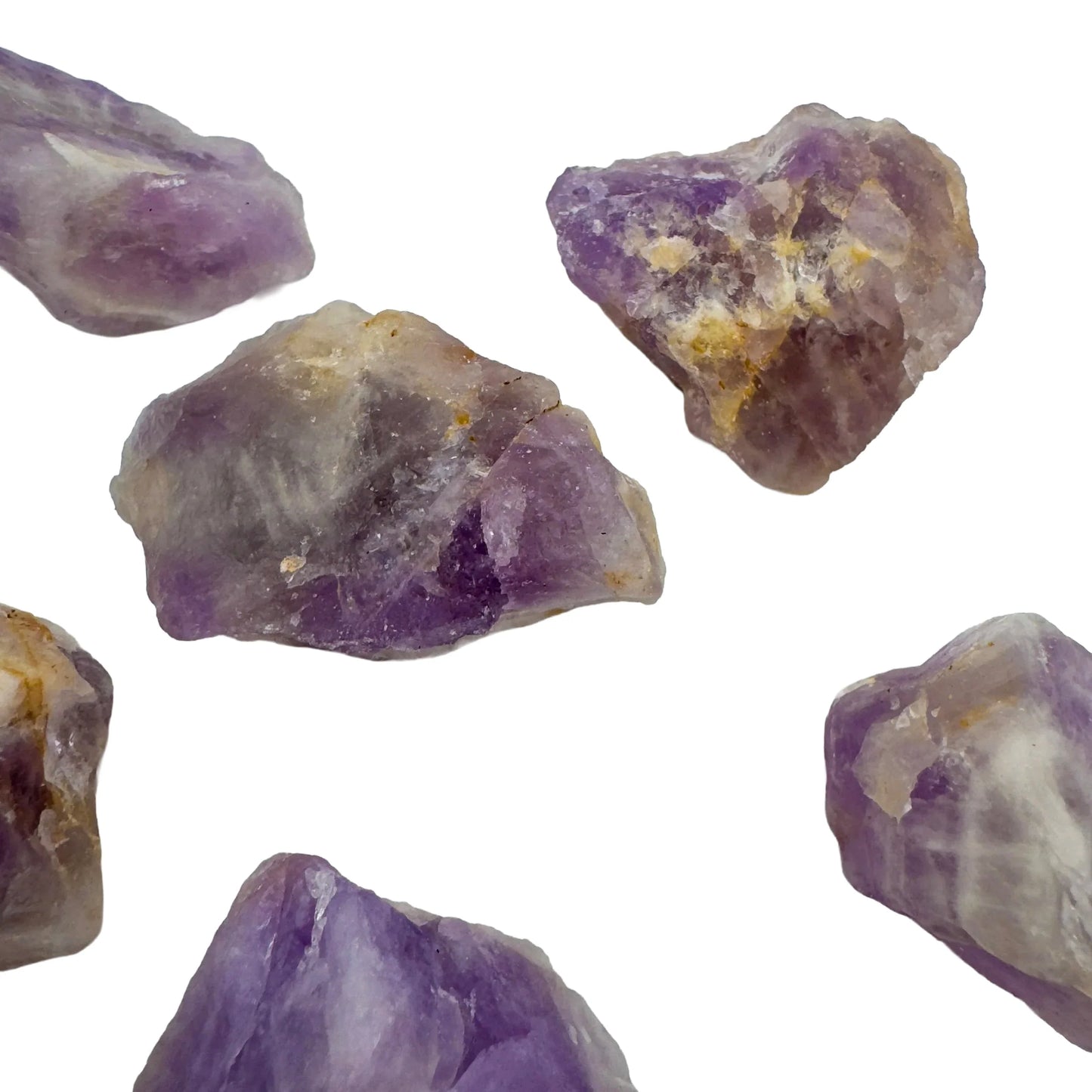 In-hand view of a Amethyst raw stone held against natural backdrop.