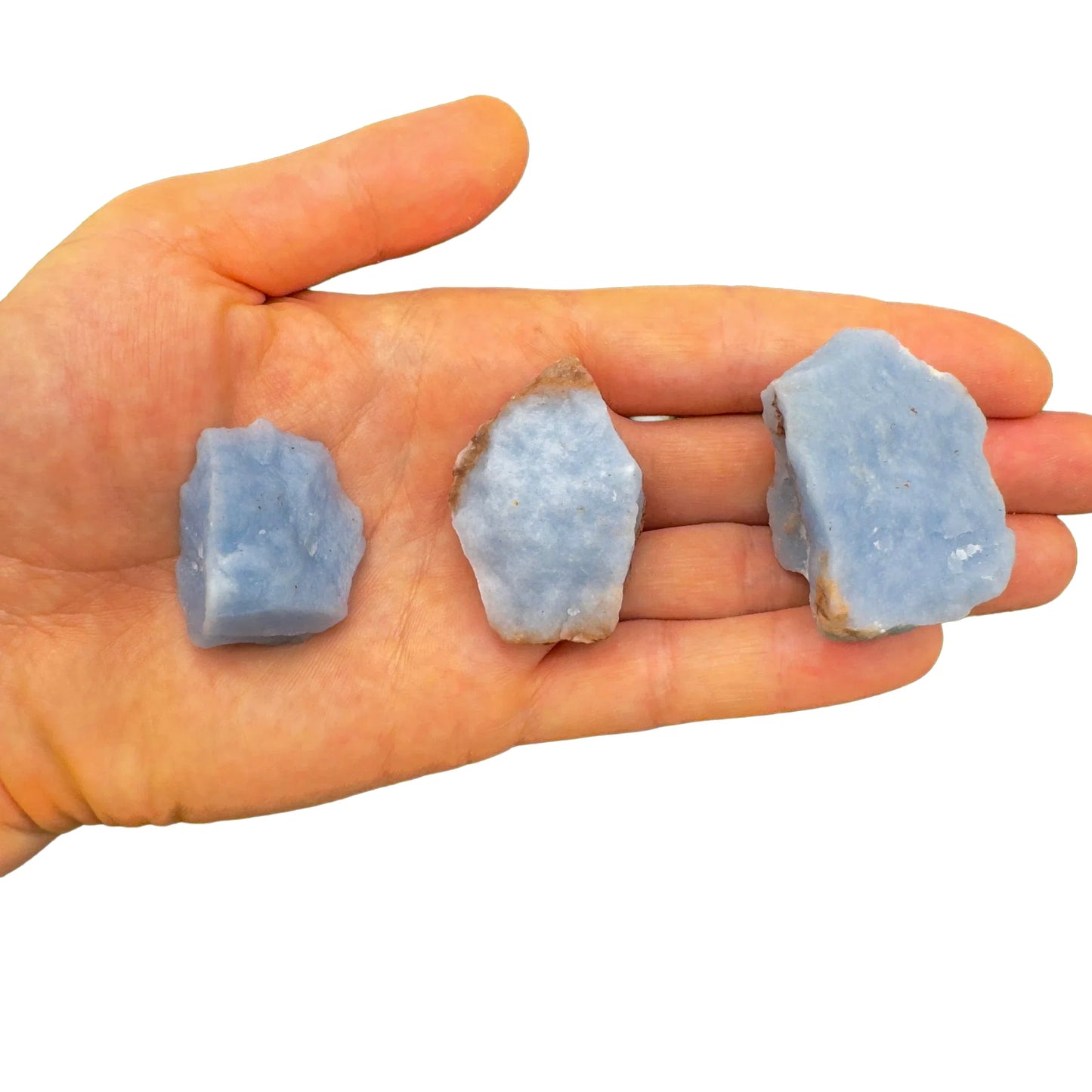 Palm-scale view of a Angelite raw stone held against natural backdrop, hand-selected from Huarochirí, Peru.