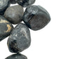 Set against a soft backdrop is an Apache Tear stone, shown at hand scale.