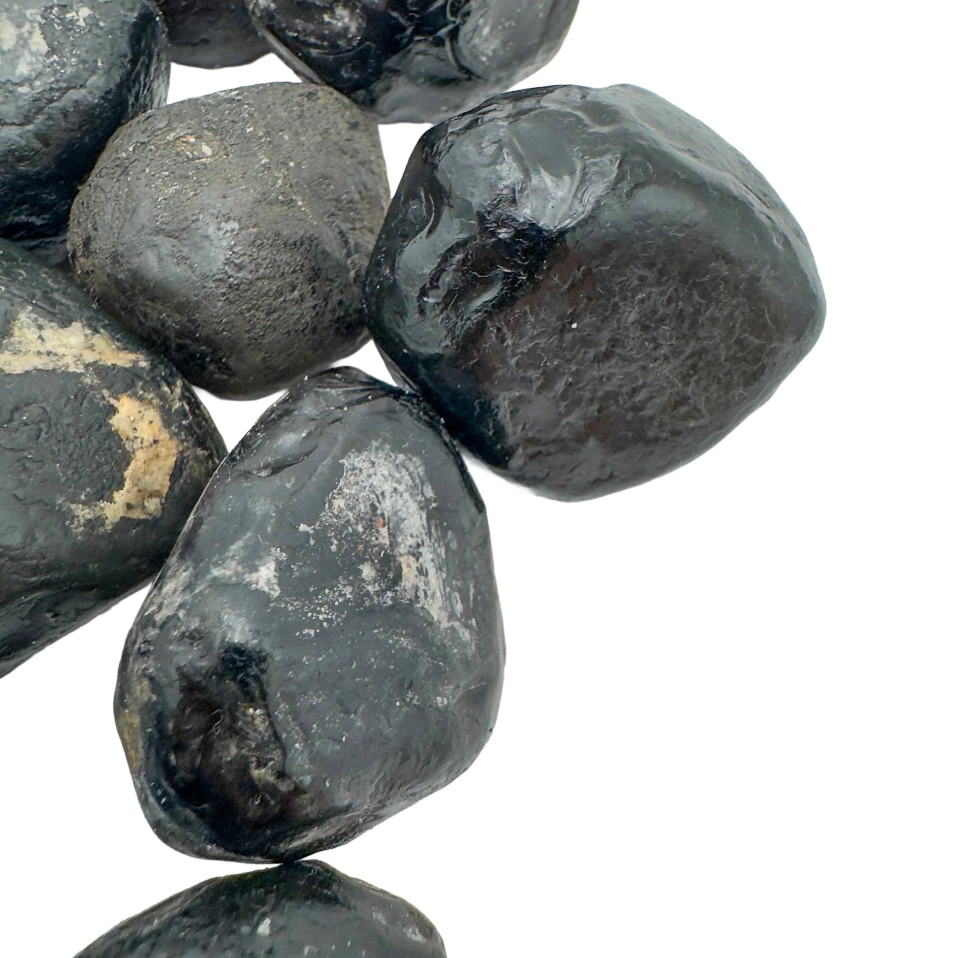 Set against a soft backdrop is an Apache Tear stone, shown at hand scale.