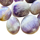 Daylight view of a Banded Amethyst palm stone held against natural backdrop.