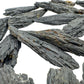 In-hand view of one Black Kyanite raw stone for scale, sourced from Brazil.