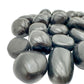 Palm-scale view of one Black Onyx tumbled stone for scale, Peru-sourced, hand-selected from Ancash, Peru.