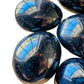 Close-up of Black Tourmaline palm stone, showing natural texture.